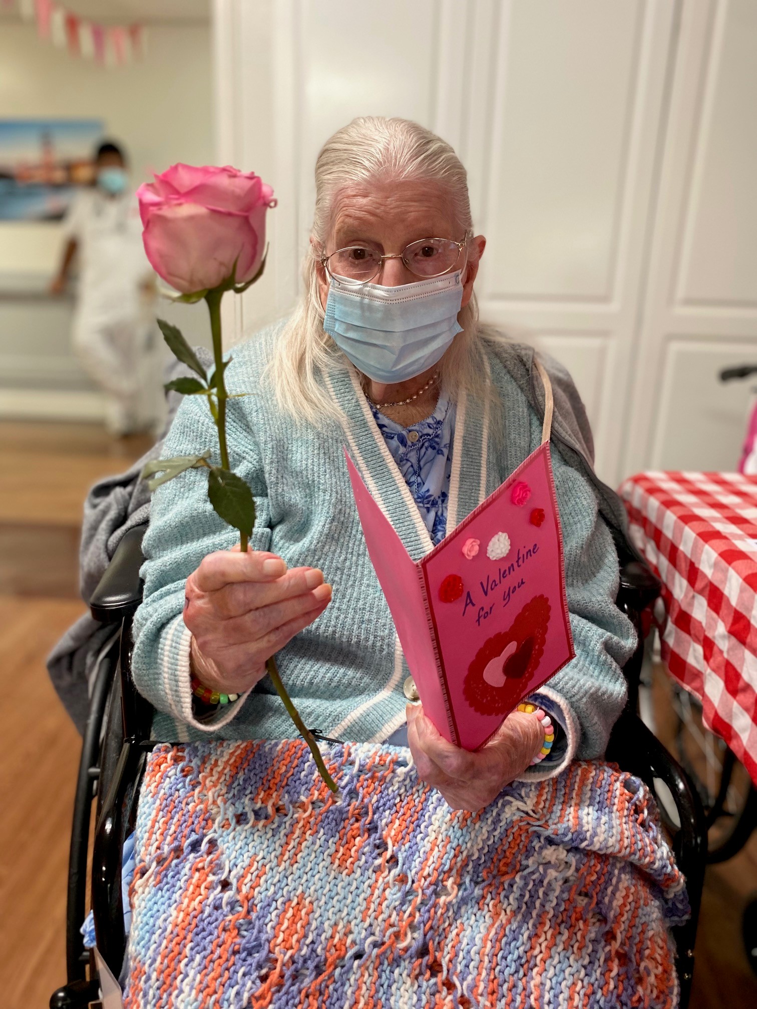 older adult holding a valentine card and rose